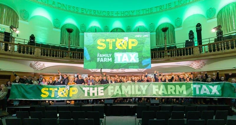 A big group of NFU members at the mass lobby holding holding a sign saying Stop the Family Farm Tax