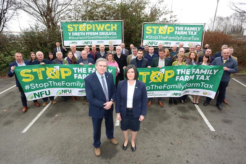 NFU Cymru Council members standing with Stop The Family Farm Tax banners