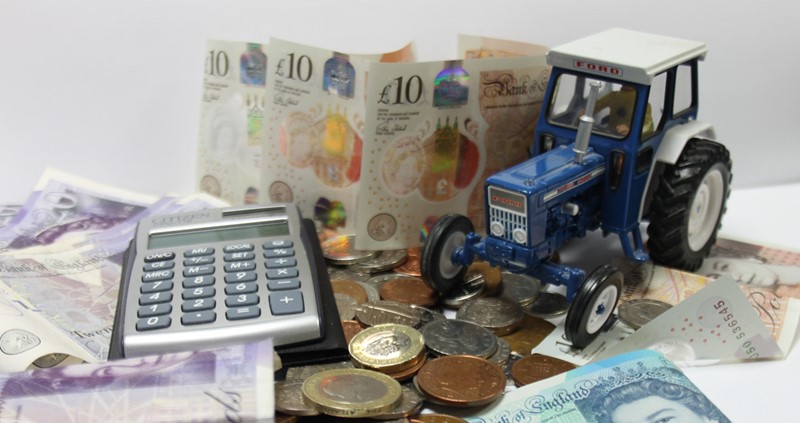 A calculator with money and a toy tractor