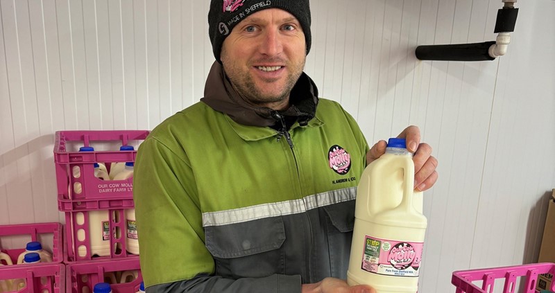 A photo of Eddie Andrew from Our Cow Molly showing the Stop The Family Farm Tax stickers on his milk