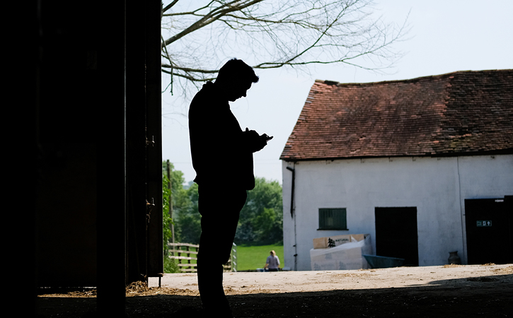 An image of a farmer in a farming building looking at their phone