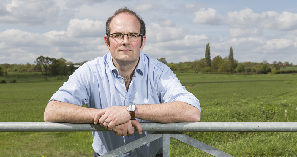 NFU Crops Board Chairman Tom Bradshaw leans on a fence to an arable field
